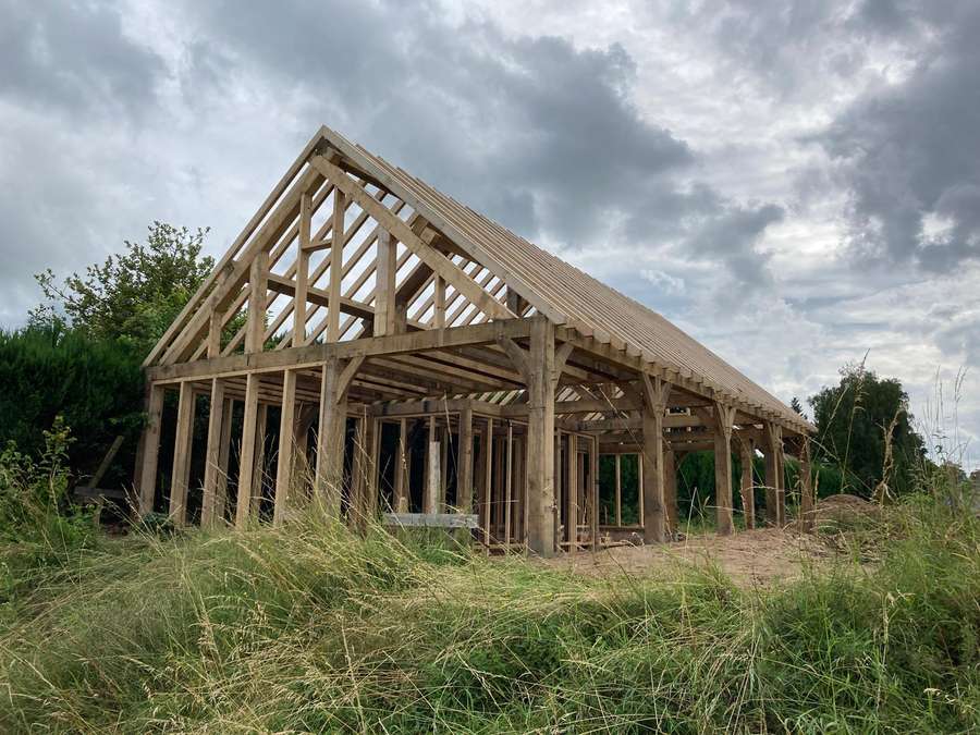 Ossature de chêne d'une maison levée sous un ciel d'orage